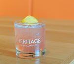 A light pink cocktail featuring HDC Peach Vodka in a Heritage Distilling Co. tumbler with a lemon wedge garnish.