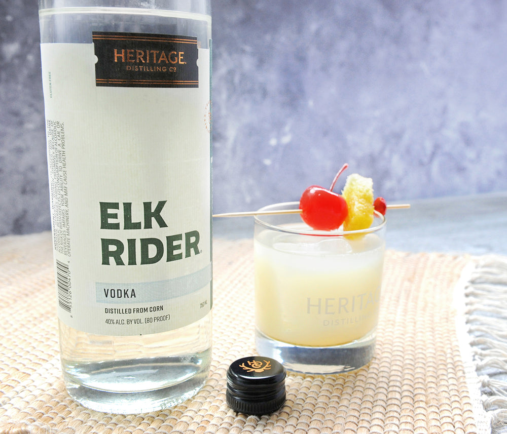 
                  
                    A 750ml bottle of HDC Elk Rider Vodka and a tropical cocktail with fruit garnishes.
                  
                