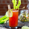 The Bloody Caesar cocktail garnished with celery, olives, and a lime wheel.