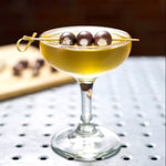 The D's Seasoned Greek Martini served in a martini glass with Feta cheese stuffed Kalamata olives.