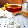 A HDC Elk Rider Rye Whiskey cocktail in a coupe glass with an orange peel twist garnish.
