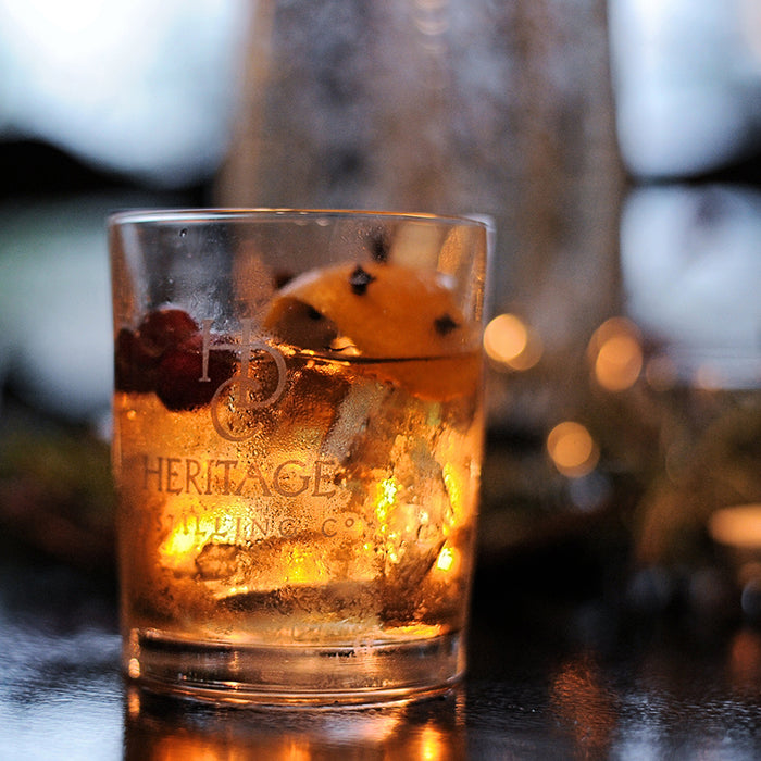 The perfect fall drink in a Heritage Distilling Co. branded tumbler features HDC Elk Rider Bourbon. It is garnished with orange peel and cranberries on top.