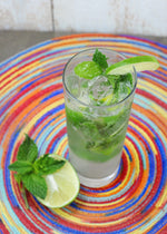 A tall glass of Cucumber Lime Vodka Gimlet featuring HDC Elk Rider Vodka with cucumber and basil garnishes.