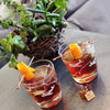 Two glasses of The Revolver Cocktail that features both HDC Elk Rider Bourbon and HDC Coffee Vodka poured over ice with orange twist garnishes.