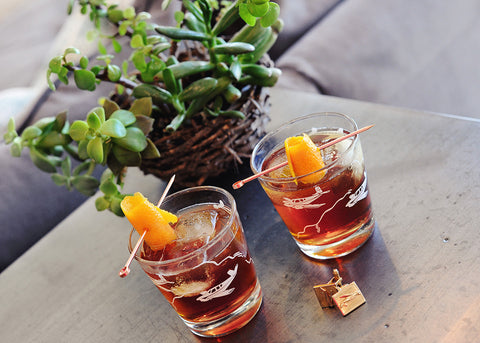 Two glasses of The Revolver Cocktail that features both HDC Elk Rider Bourbon and HDC Coffee Vodka poured over ice with orange twist garnishes.