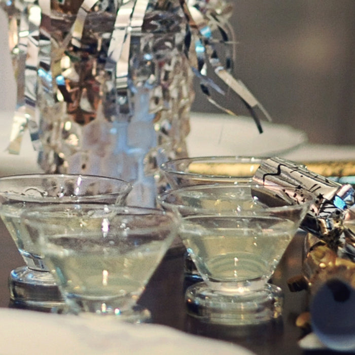 Silver party decor and fancy stemless martini glasses full of a HDC Citrus Vodka and HDC Blood Orange Vodka-based drink.