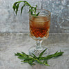 A goblet of Smoky Elk Rider Cocktail featuring both HDC Elk Rider Bourbon and HDC Elk Rider Blended Whiskey topped with fresh tarragon leaves.