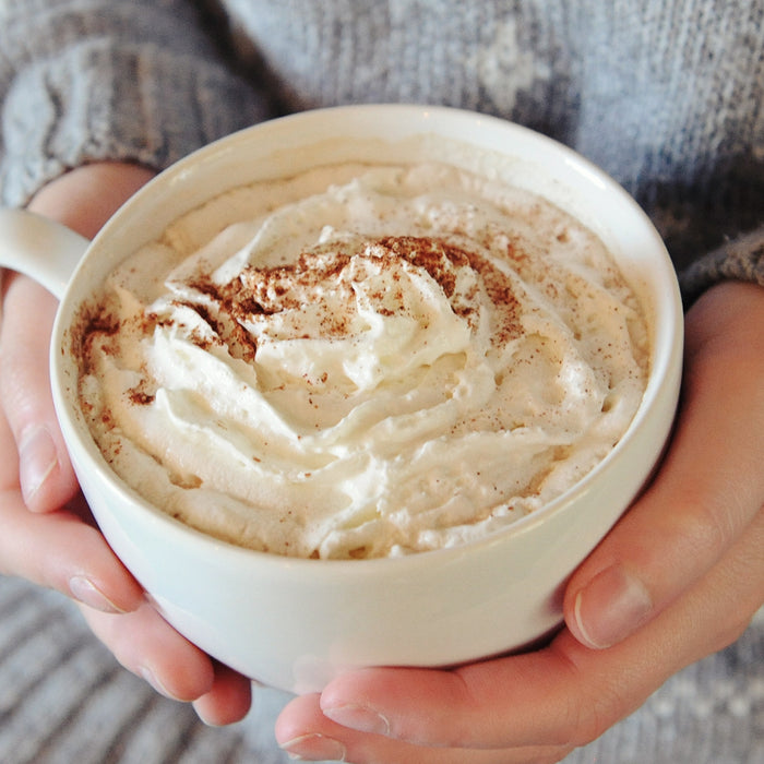A large mug full of this HDC Vanilla Vodka-based cocktail with whipped cream and chocolate sprinkles on top.