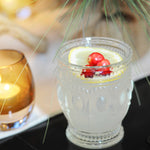A refreshing punch in an elegant punch cup with a lemon wheel and fresh cranberries to garnish.