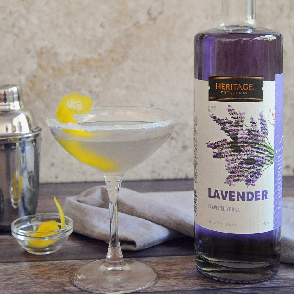 A bottle of HDC Lavender Vodka, a metal shaker, and a lemon drop cocktail made with that spirit.