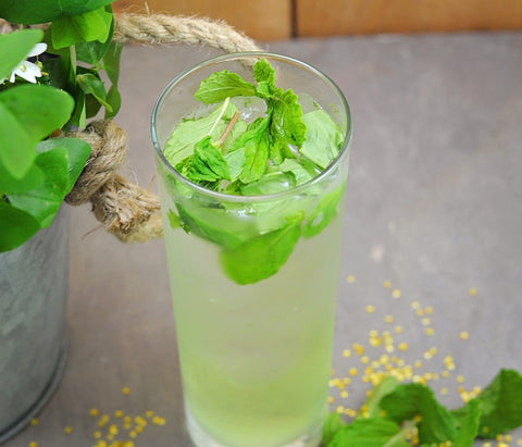 A light and refreshing light green cocktail with mint and basil leaves placed in the drink.