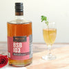 A red rose, a bottle of BSB 103, and the Julep 103 cocktail in a cocktail goblet.