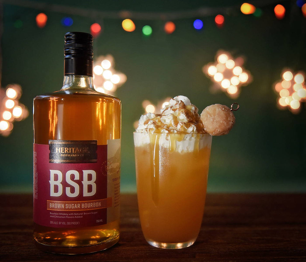 A bottle of BSB - Brown Sugar Bourbon and a tall glass of BSB Apple Cider topped with whipped cream, caramel sauce, cinnamon, and a donut (there is both a hot and cold version available).
