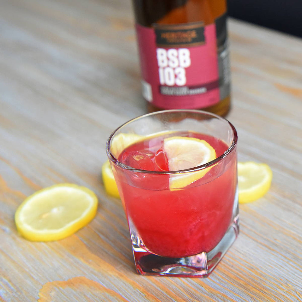 A glass of Blackberry Smash in a glass is pictured in front of a bottle of BSB 103.