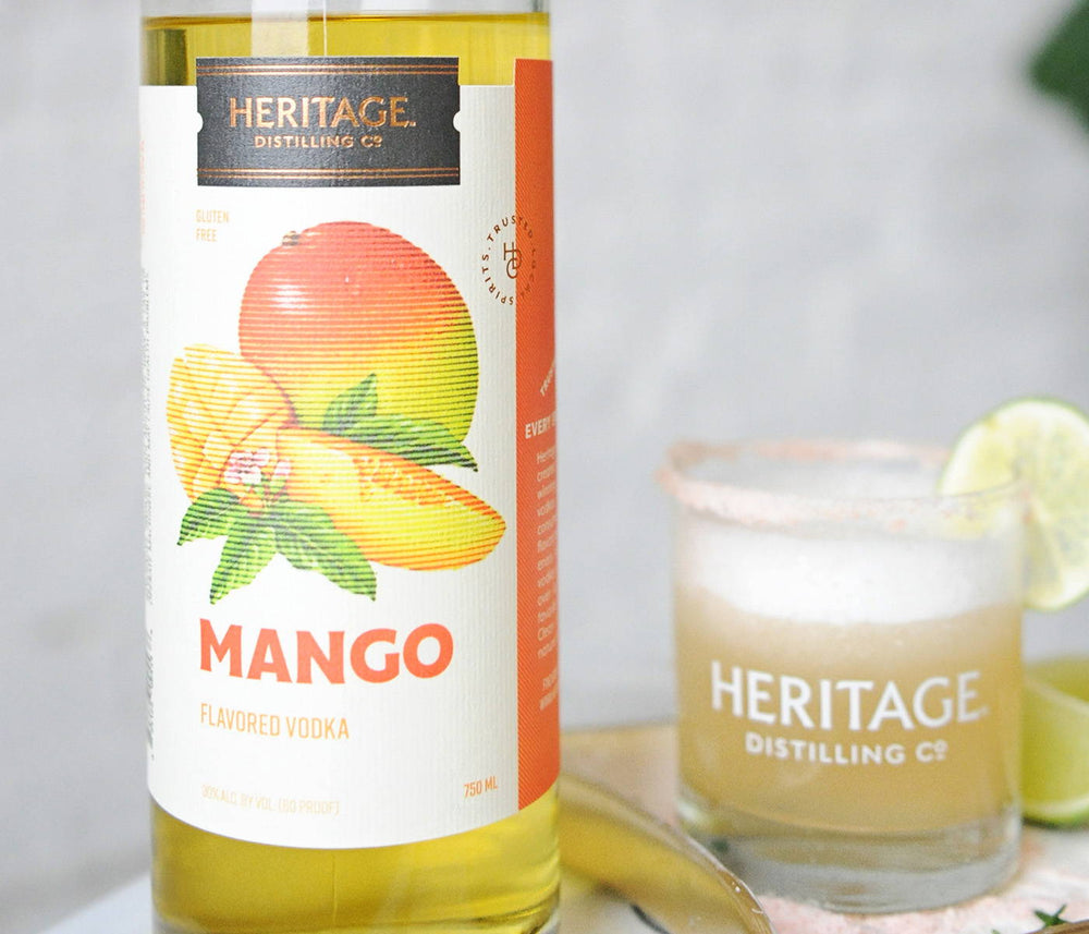 A bottle of HDC Mango Vodka and a Mango Vodkarita in a tumbler of ice.