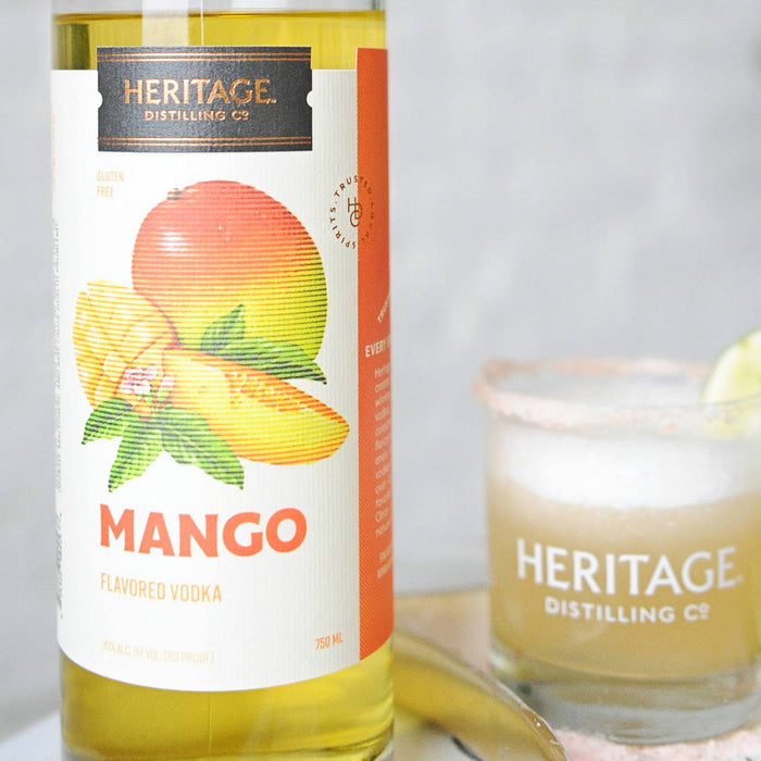 A bottle of HDC Mango Vodka and a Mango Vodkarita in a tumbler of ice.
