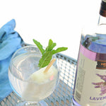 A bottle of HDC Lavender Vodka and a full glass of Lavender Popsicle Cocktail with a lemon popsicle placed inside it.