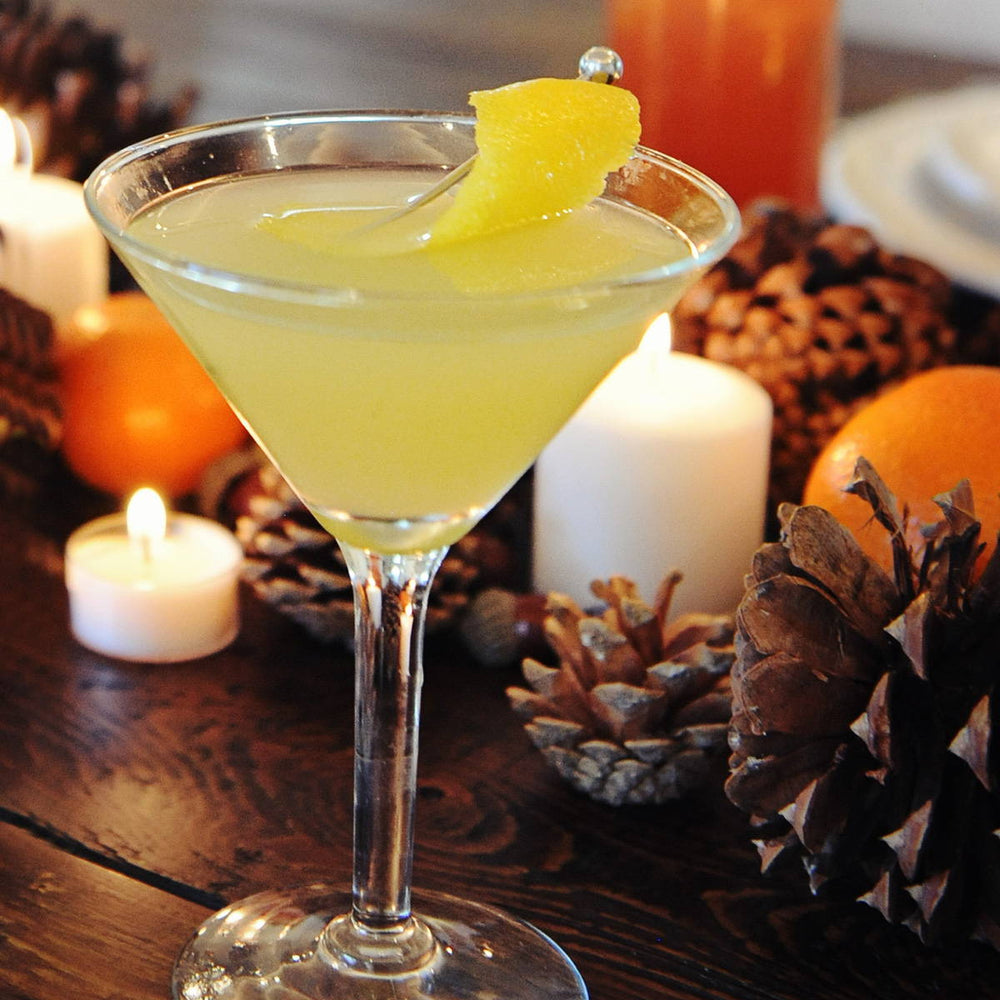 A bright yellow cocktail that uses HDC Citrus Vodka and other mixers poured into a martini glass with a lemon peel garnish.
