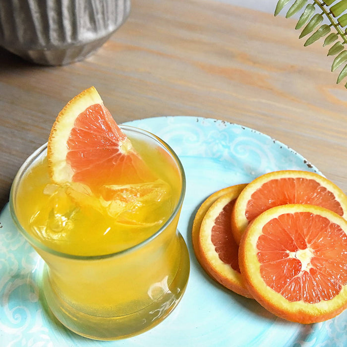 A bright yellow HDC Citrus vodka cocktail with orange wedge garnishes.