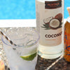A bottle of HDC Coconut Vodka is next to a full Sparkling Mango Coconut Drink with a lime wedge in it.
