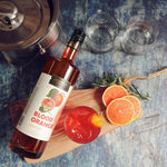 A bottles of HDC Blood Orange Vodka and a vibrant cocktail with fresh garnishes.