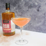 This picture has a cocktail goblet with the Harvest Moon cocktail and a bottle of BSB - Brown Sugar Bourbon.