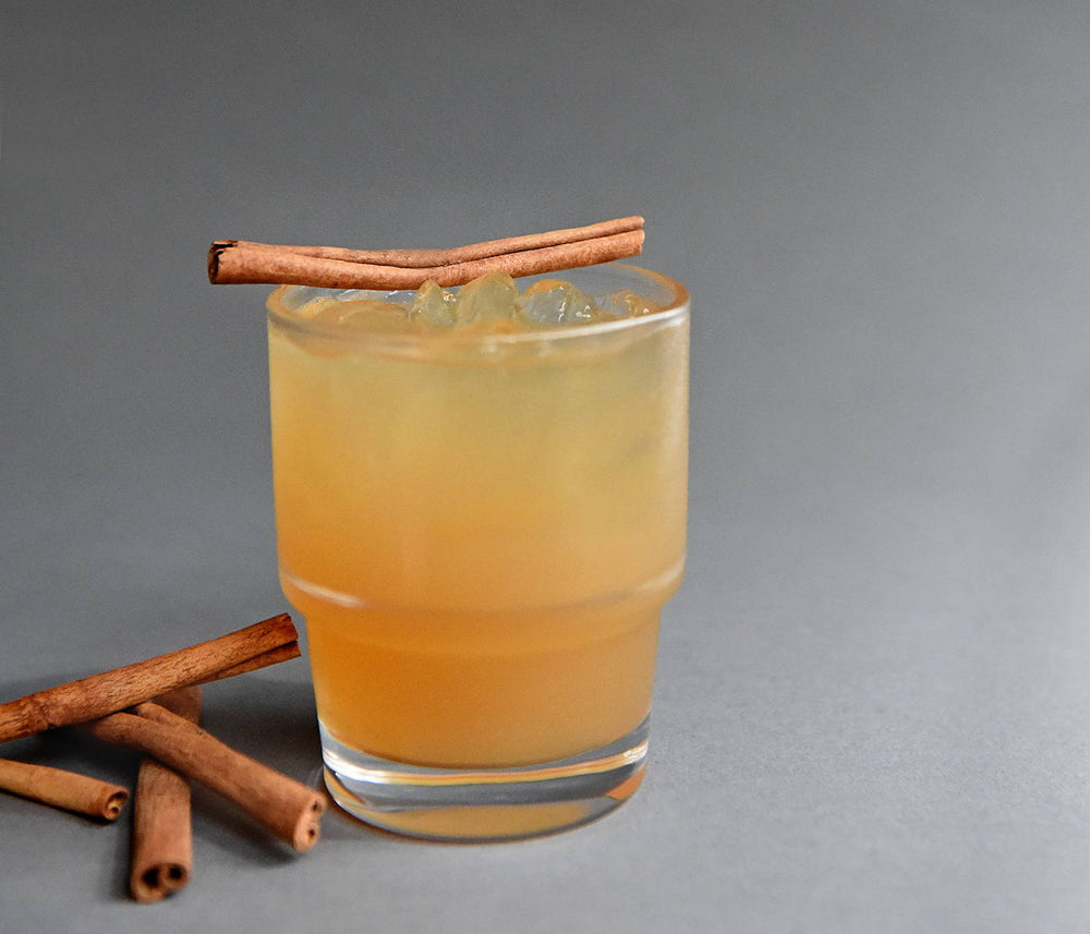 A glass of BSB Cider with cinnamon sticks on and around the drink.