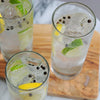 Three highball glasses of a cocktail made with HDC Bestemors Aquavit and garnished with lemon, lime, and peppercorns.