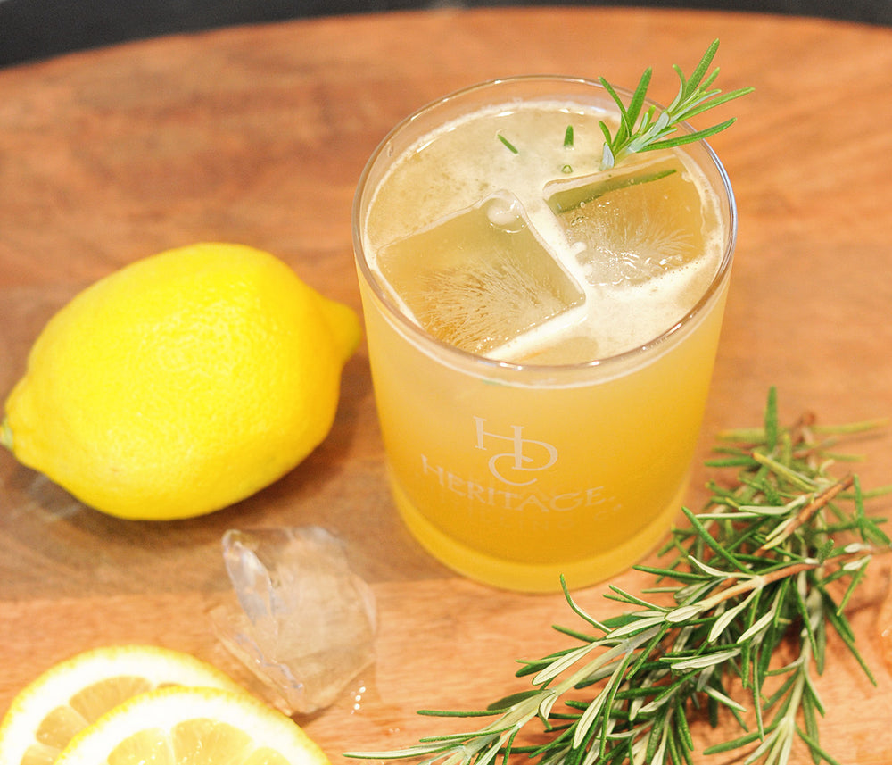 A bright yellow cocktail featuring HDC Elk Rider Rye and garnished with rosemary.
