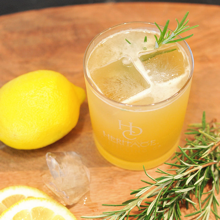 A bright yellow cocktail featuring HDC Elk Rider Rye and garnished with rosemary.