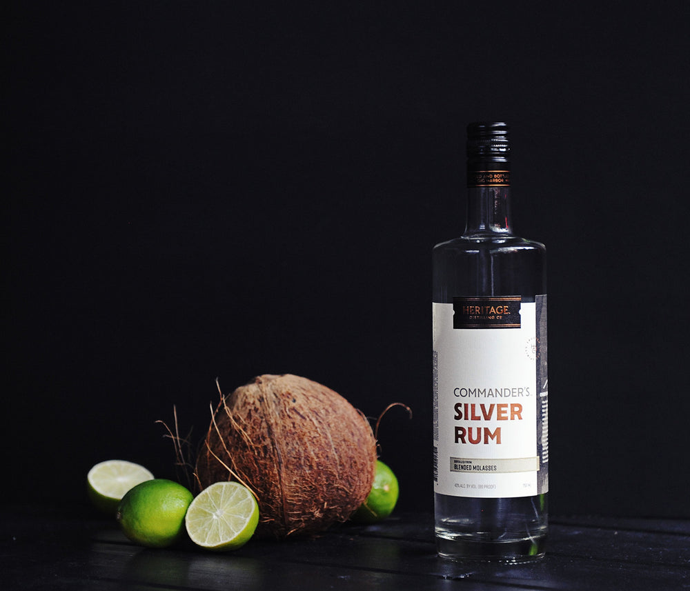 
                  
                    A 750ml bottle of HDC Commander's Silver Rum next to a coconut and some limes.
                  
                