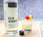 A 750ml bottle of HDC Elk Rider Vodka and a tropical cocktail with fruit garnishes.