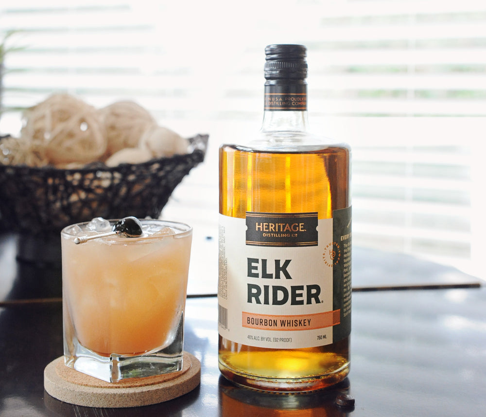 
                  
                    A 750ml bottle of HDC Elk Rider Bourbon Whiskey on a window sill with a cocktail next to it.
                  
                