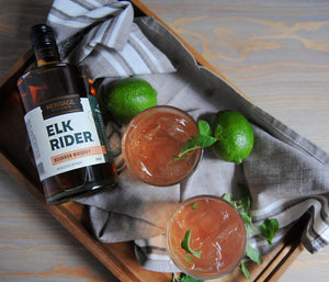 
                  
                    A 750ml bottle of HDC Elk Rider Bourbon Whiskey and two cocktails next to it.
                  
                